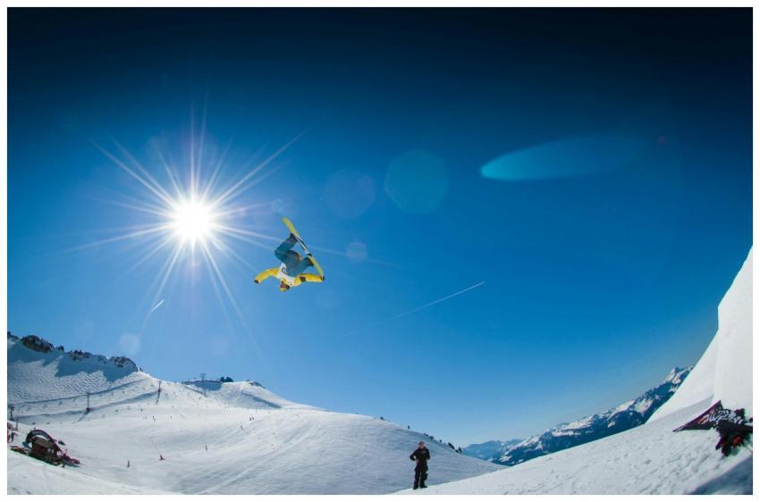 Snowboarder executing a freestyle trick in the sun