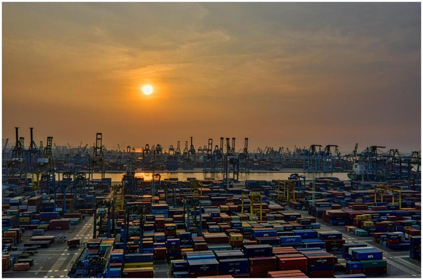 Sunset over a bustling seaport filled with stacked