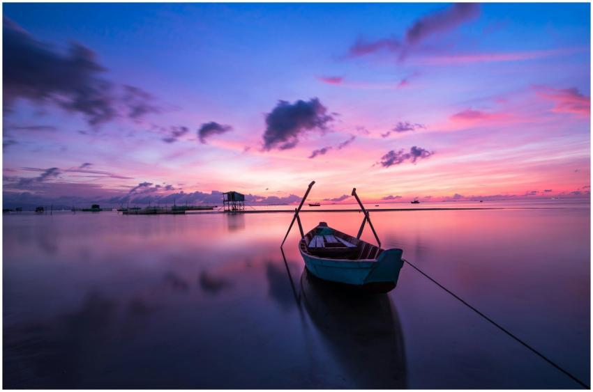A tranquil tropical sunrise with a lone boat on ca