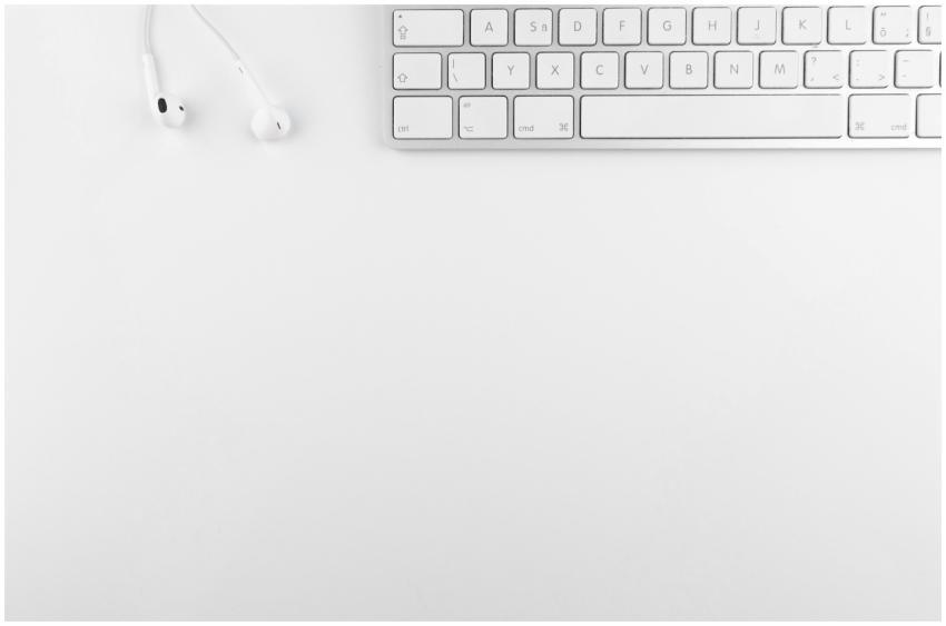 Top view of a white minimalist desk featuring a ke