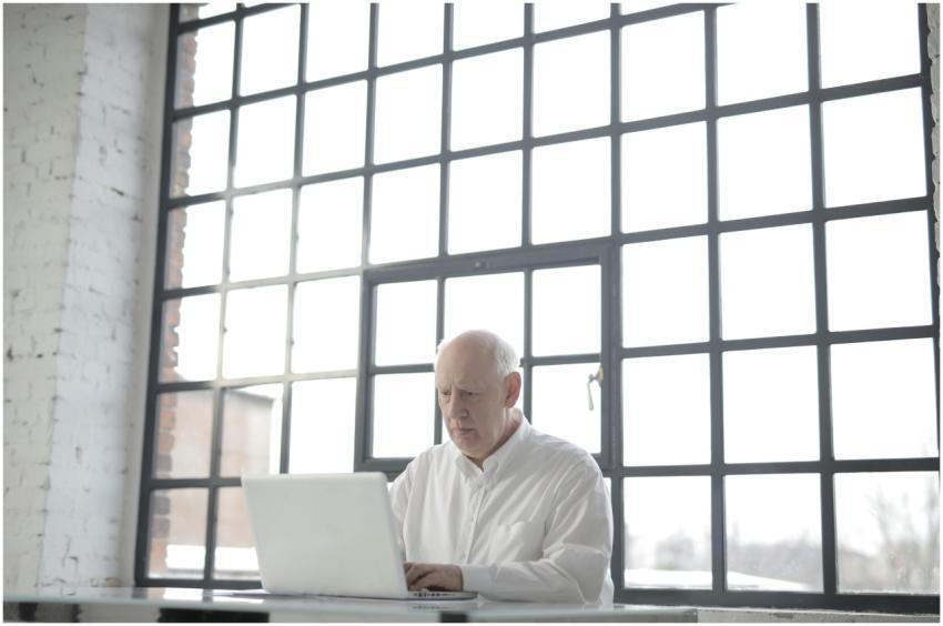 Focused senior man working on laptop in bright mod