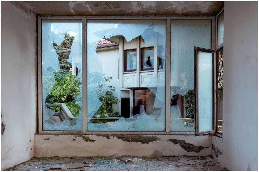 A shattered window revealing an abandoned building