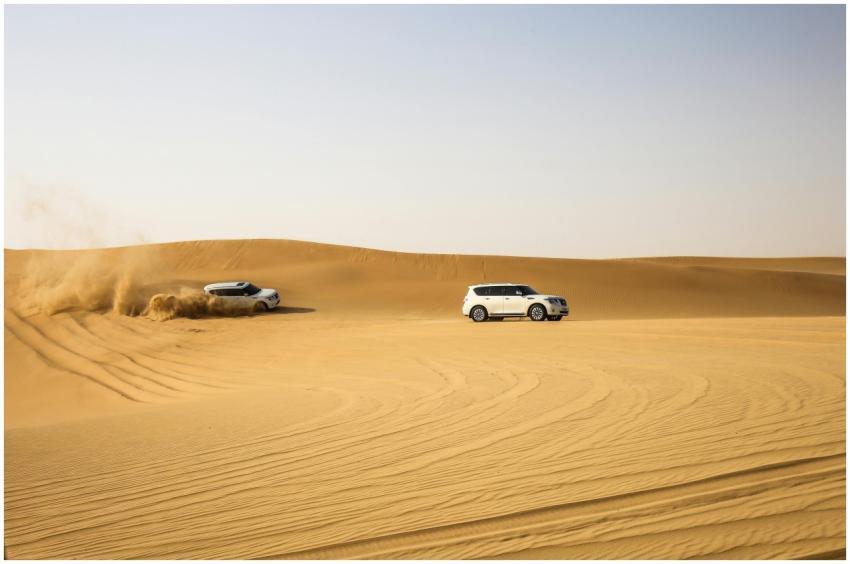 Two SUVs driving through the dunes in Abu Dhabi de