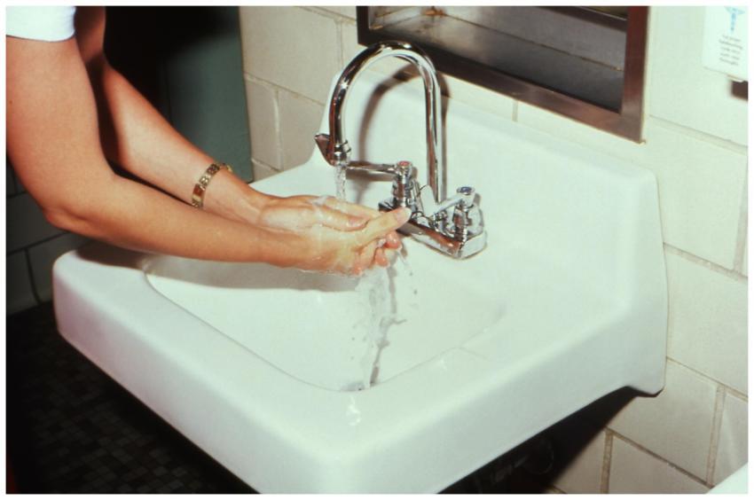 A woman washing hands at a bathroom sink, highligh