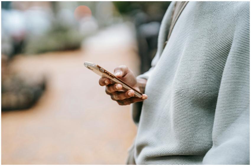 A person casually uses a smartphone outdoors in an