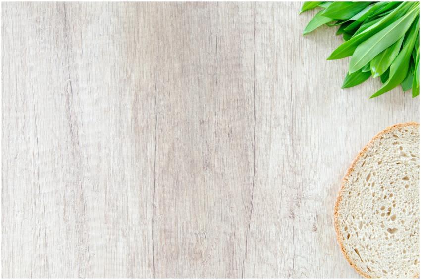 Slice of bread and green leaves on a wooden surfac