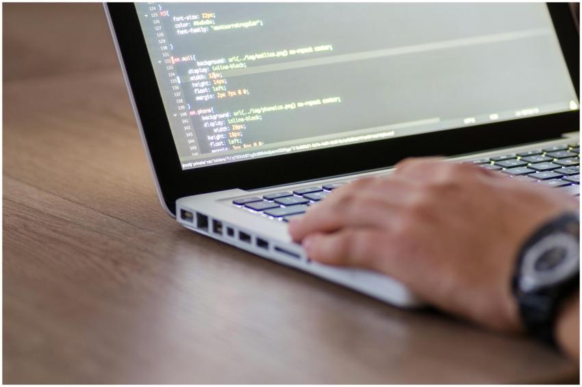 Person coding on a laptop with HTML code on screen