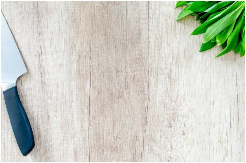 Fresh herbs and a chef knife on a wooden surface w