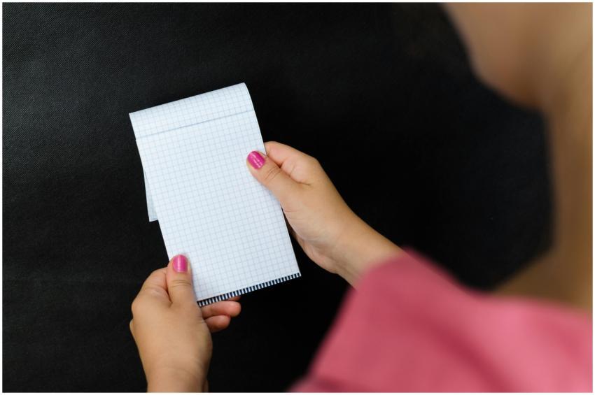 A close-up of a woman holding a small notepad with