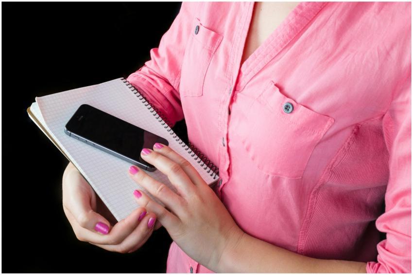 Close-up of a woman in a pink shirt holding a smar
