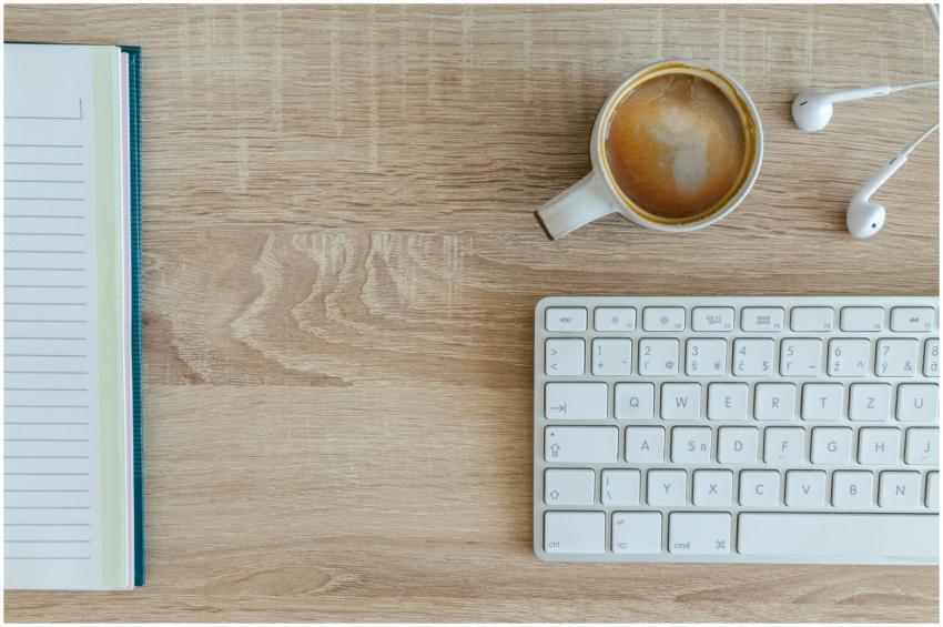 Flat lay of a workspace featuring coffee, a keyboa