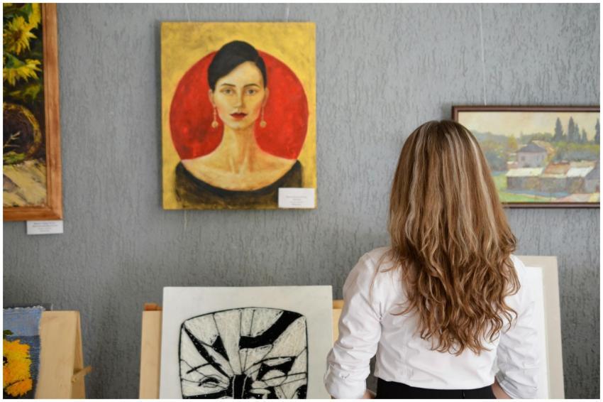 A woman views paintings in an art gallery, appreci
