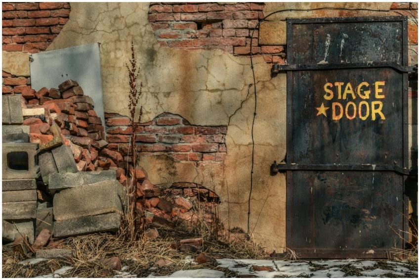 An aged, rustic stage door amidst cracked walls an