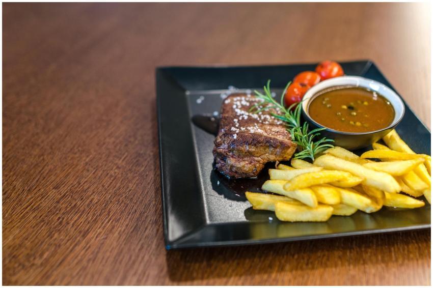 Close-up of a savory steak with fries, cherry toma