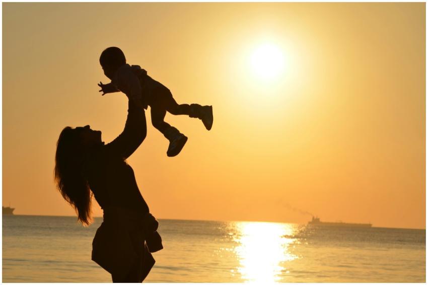 Silhouette of a mother lifting her child at a suns