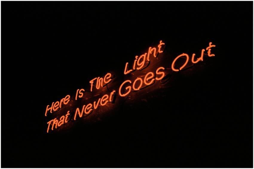 A glowing neon sign reads 'Here is the light that