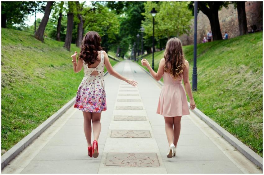 Back view of two stylish women walking along a tre