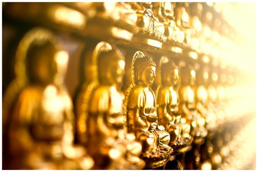 Row of golden Buddha statues in soft focus, symbol