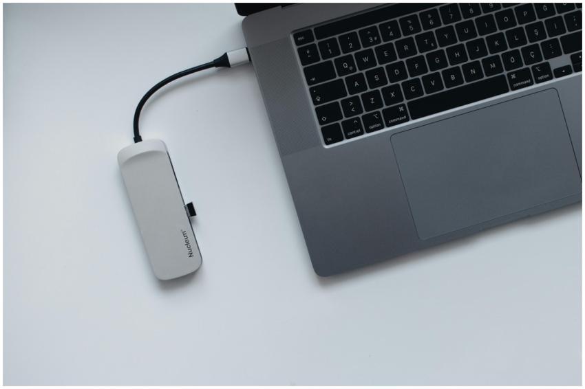 A sleek laptop connected to a USB hub on a minimal