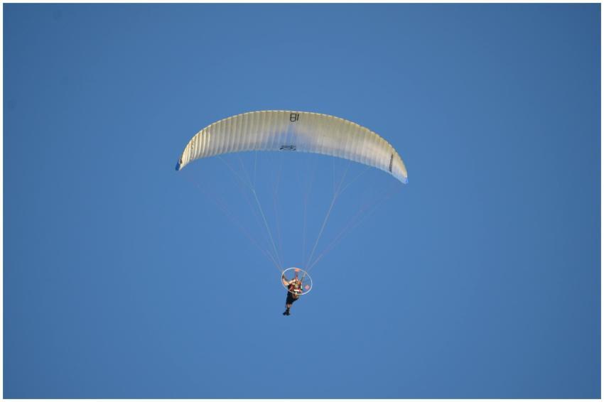 A thrilling shot of a paraglider soaring high agai