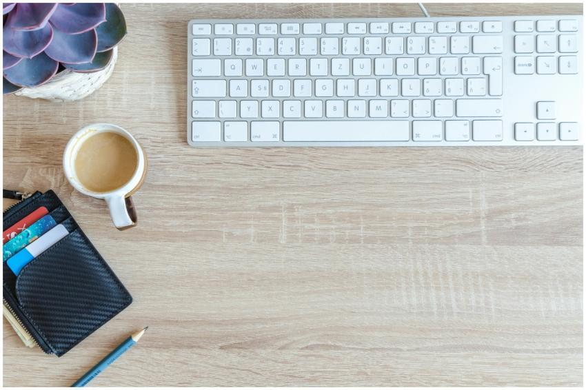 An organized workspace with a keyboard, coffee cup