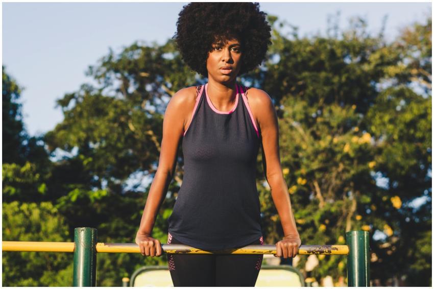 Woman exercising on outdoor bars during sunny day,