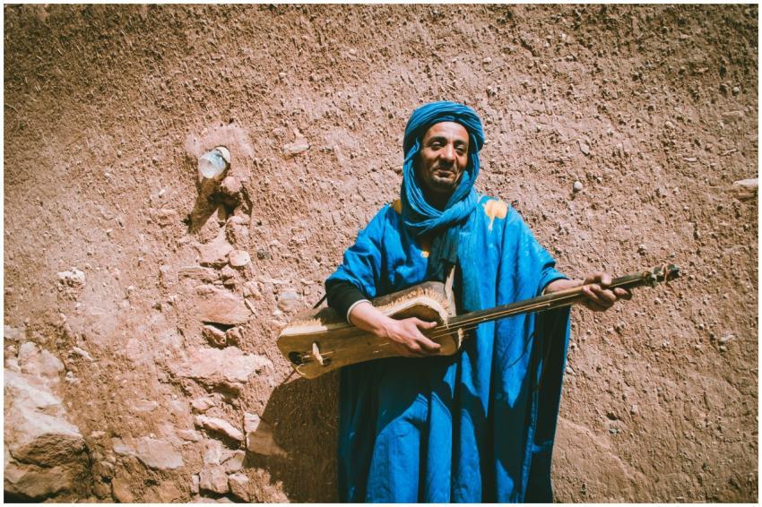 A Moroccan man in blue robes plays a traditional s