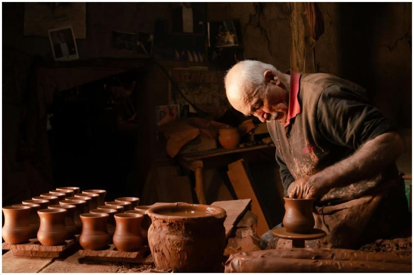 Elderly artisan shaping pottery with care in a tra