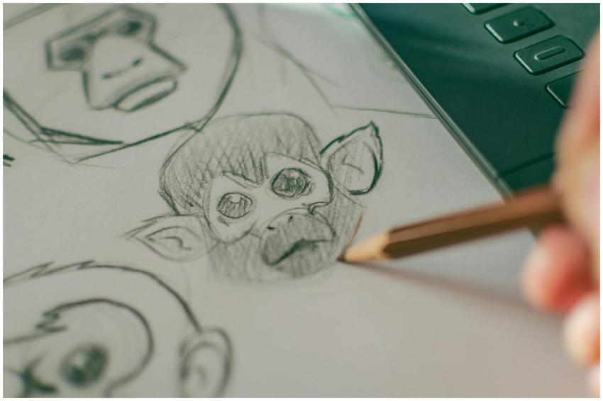 Close-up of hand sketching monkey faces on paper,