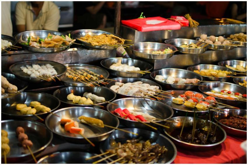 Assorted Asian street food skewers arranged on met