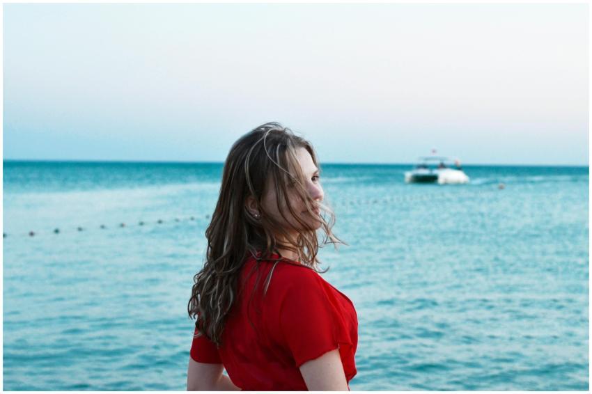 Woman in a red dress enjoys a serene beach sunset