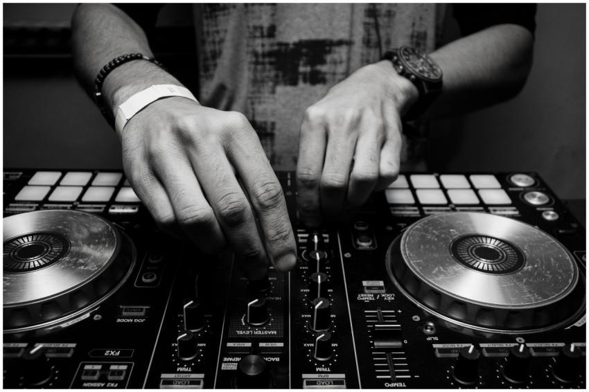 Close-up of a DJ's hands adjusting controls on a m