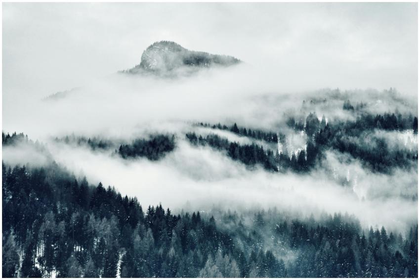 Scenic view of a snow-covered mountain enveloped i