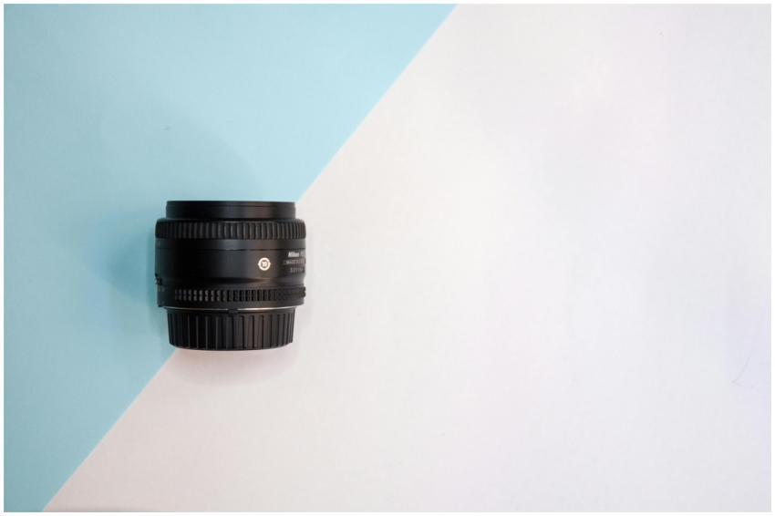 Black camera lens displayed on a minimalistic blue
