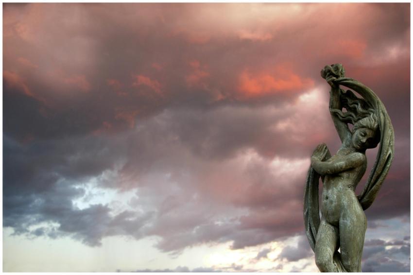A classical statue silhouetted against a dramatic