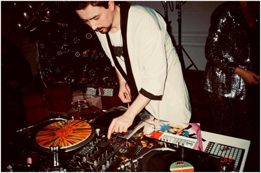 A DJ mixing records at a lively indoor party, surr