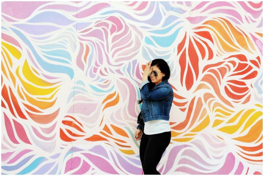 A woman in a denim jacket poses joyfully against a
