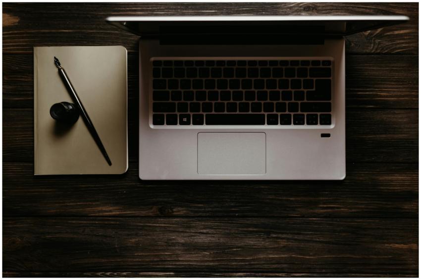 A stylish flat lay of a laptop with a notebook and