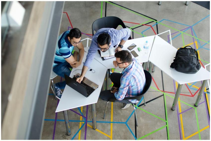 Three men collaborating over a laptop in a modern,