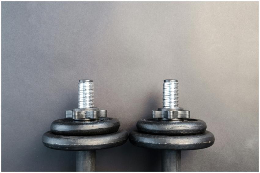 Close-up of two iron dumbbells on a gray backgroun