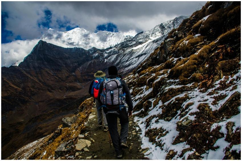 Two hikers navigating a snowy trail in rugged moun