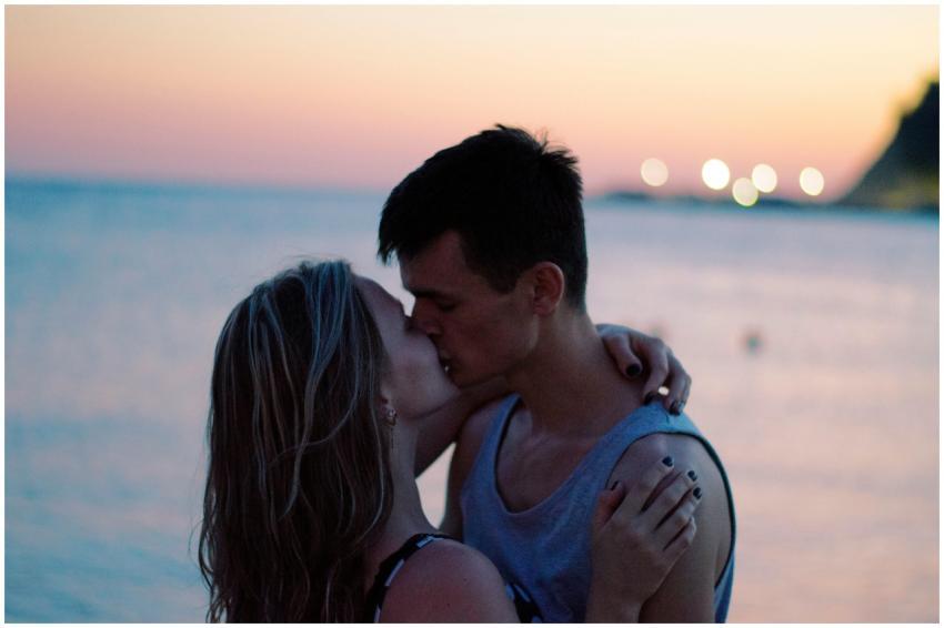A couple shares a romantic kiss at the beach durin