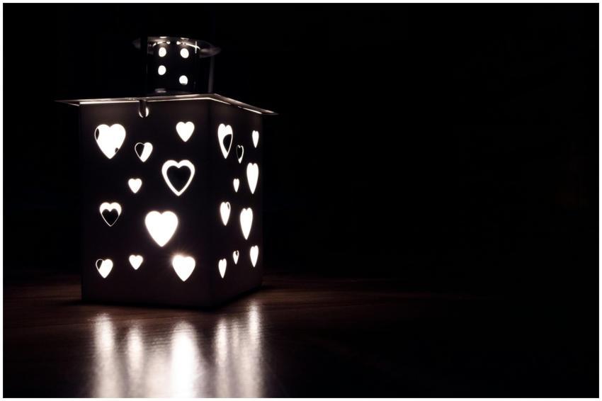 A square lantern with heart-shaped cutouts casting