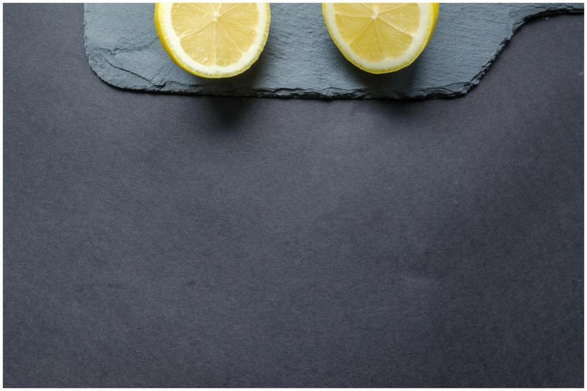 Close-up of fresh lemon halves on slate with a dar
