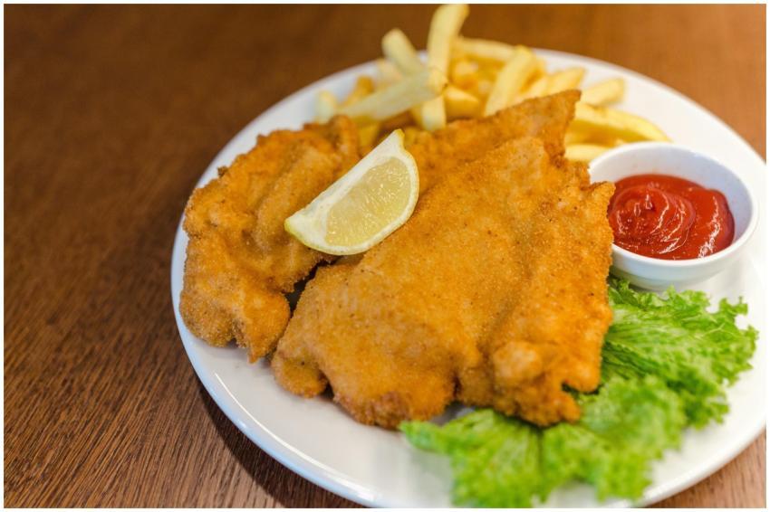 Delicious schnitzel served with fries, lettuce, le
