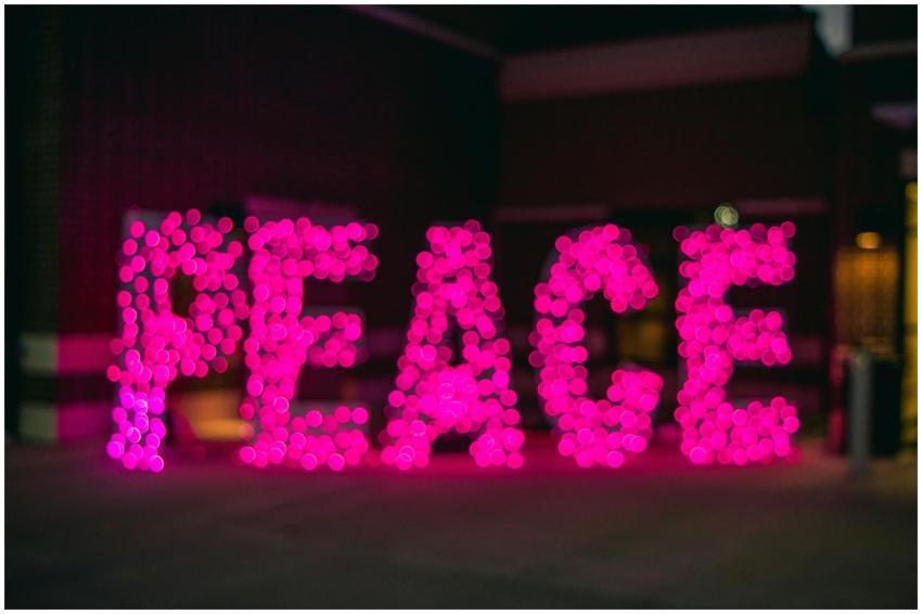 Blurred pink lights form the word 'PEACE' in an ar