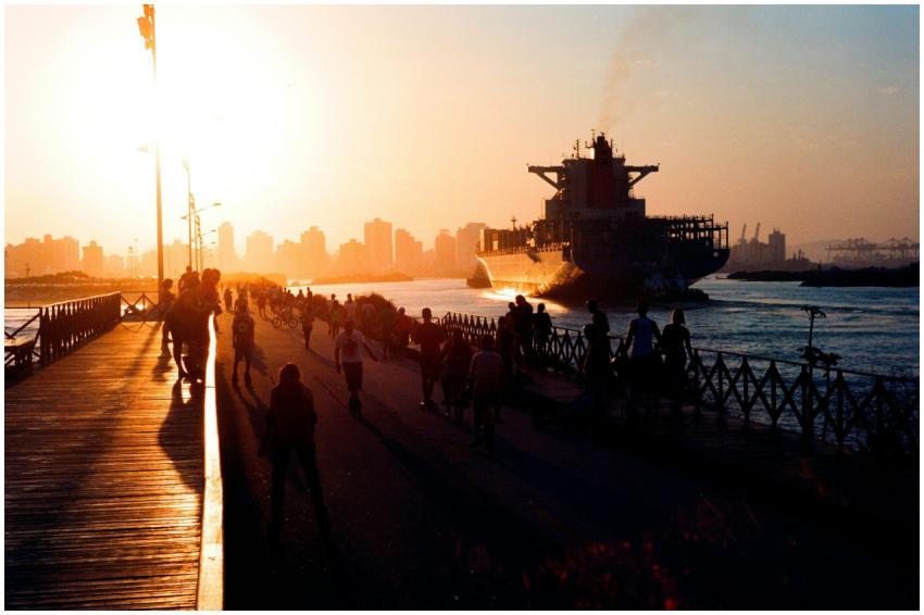 Silhouetted people and ship in Brazilian harbor du