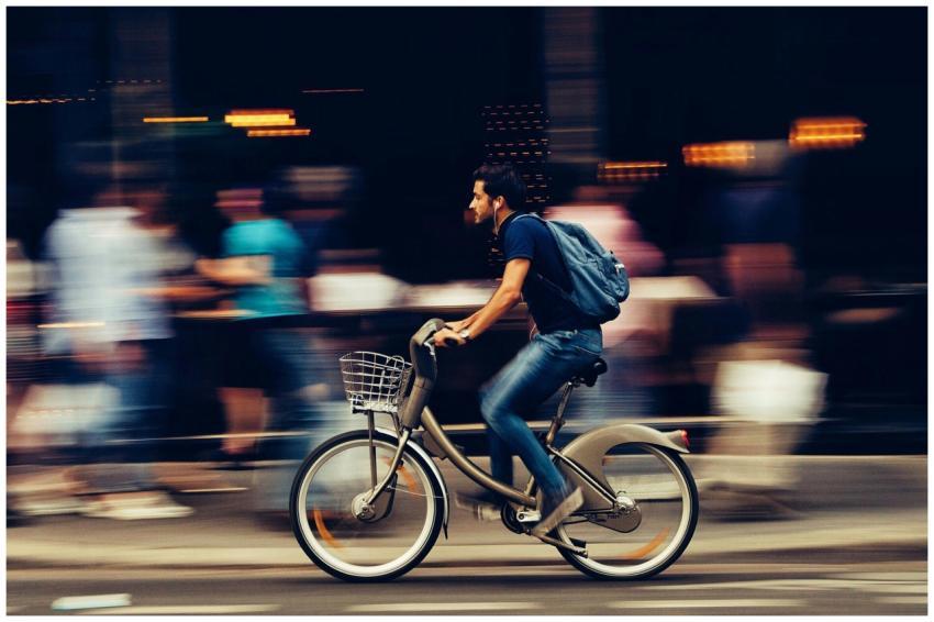 A cyclist swiftly rides through an urban street, c