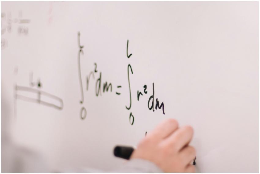 Person writing math equations on a whiteboard, foc