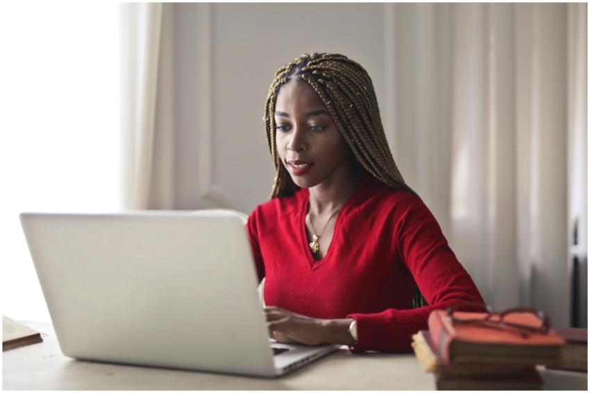 Confident woman in a red sweater working on a lapt